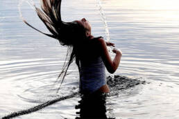 En flicka som badar i Värnen och slänger med sitt hår i vattnet.